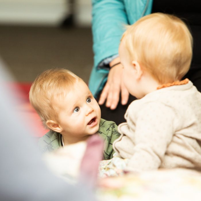 Close up of a baby at a baby class looking at another baby