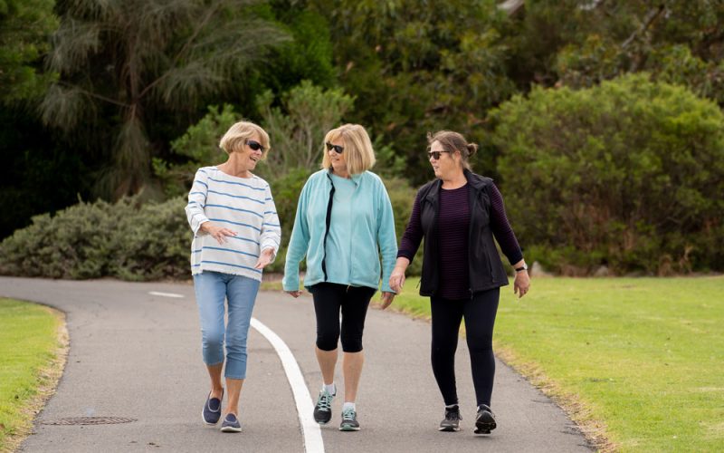 Three women walking outside on a walking path